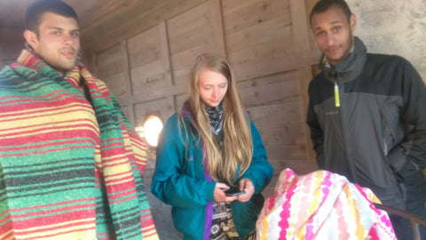Three people standing together, one holding a phone