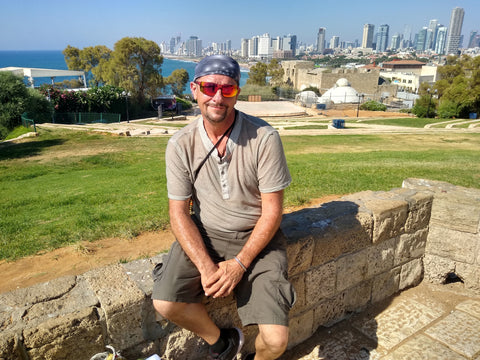 Man sitting on a stone wall with a cityscape and ocean view