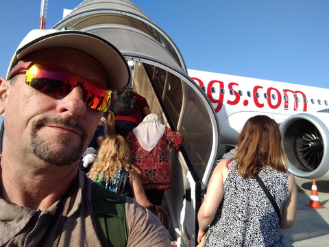 Man with sunglasses and cap standing in front of a small airplane with 'qgs.com' branding.