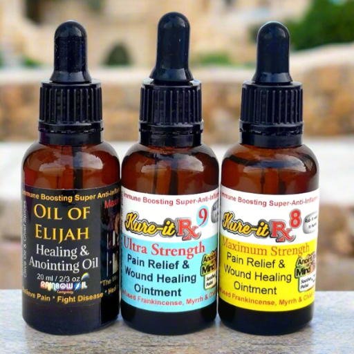 Three bottles of 'Oil of Elijah' and 'Kure-it RX' products on a surface with a blurred outdoor background.