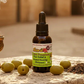 Bottle of Kure it Rx10 Bible Anointing oil for healing prayer with green label on a wooden surface with olives.