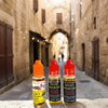 Three bottles of Good Samaritan oil on a stone ledge with a blurred alleyway background