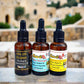 Three bottles of Kure-it anointing oil in different strengths: Oil of Elijah Ultimate Strength, Kure-it Rx9 Ultra, and Kure-it Rx8 Max Strength, with dropper caps.