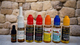 Collection of various essential oil bottles with colorful caps on a stone surface.